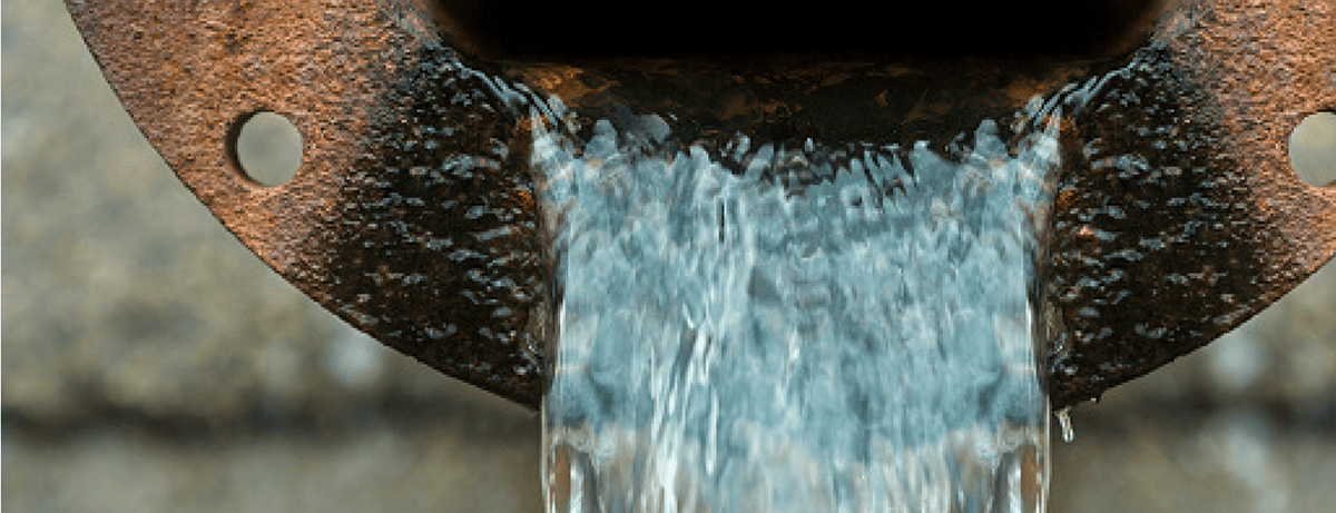 Gran tubo oxidado del que sale agua