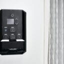 Black control panel with buttons for power, filter reset, dark mode, and quiet mode, mounted on a white wall.