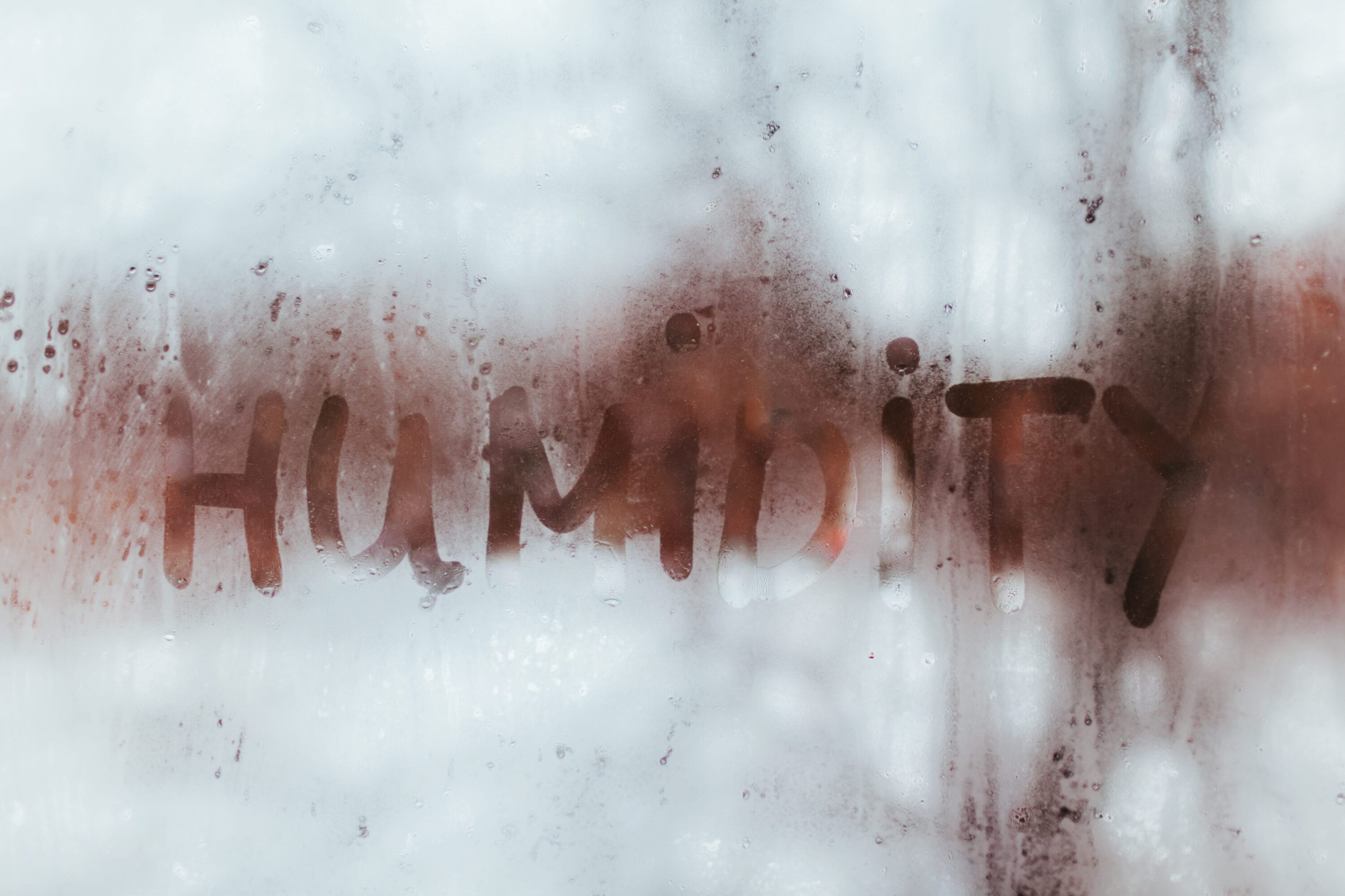 condensation on a window pane, with "humidity" written in it, depicting a high level of humidity.