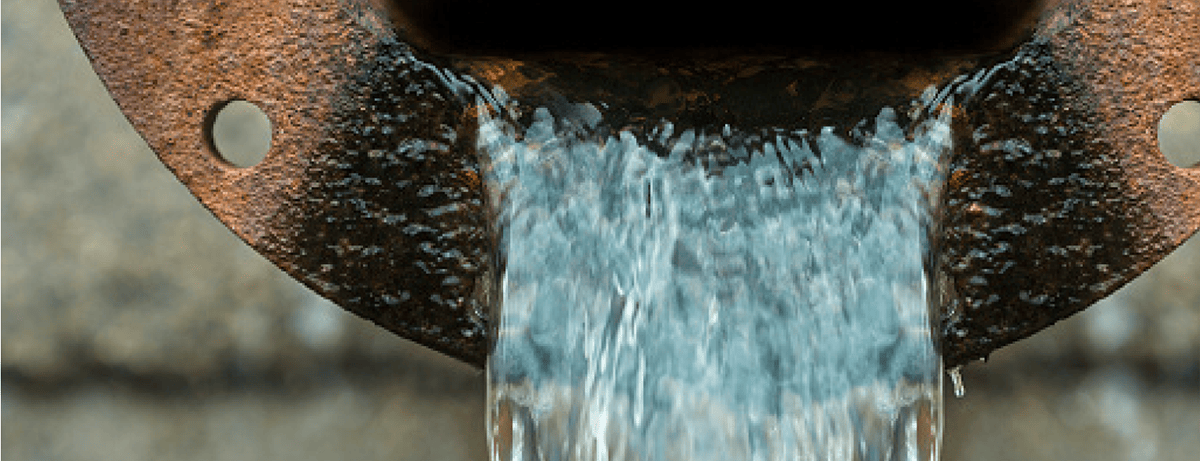 Large rusty pipe with water flowing out of it