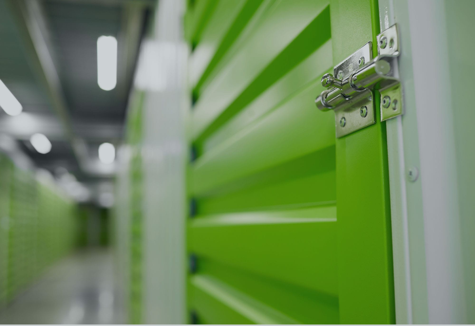 hallway of self storage facility with multiple green doors, close up of the door lock